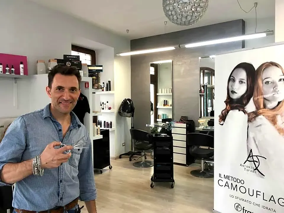 L'interno del salone: pareti grigio-argento, specchi, finestre ad arco e Matteo con le forbici
